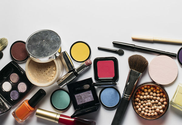 Auf der linken Seite des Bildes verstreut liegen lauter Utensilien zum Schminken, allgemein auch als Make-up bezeichnet. Dieser Sammelbegriffumfasst so verschiedene Dinge wie Rougeperlen, Lidschatten, Puder, Pinsel, Lippenstift, Nagellack und Eyelinerstifte. Die rechte Bildhälft bildet einen starken Kontrast dazu, weil sie komplett leer ist und man nur den weißen Hintergrund sieht.  